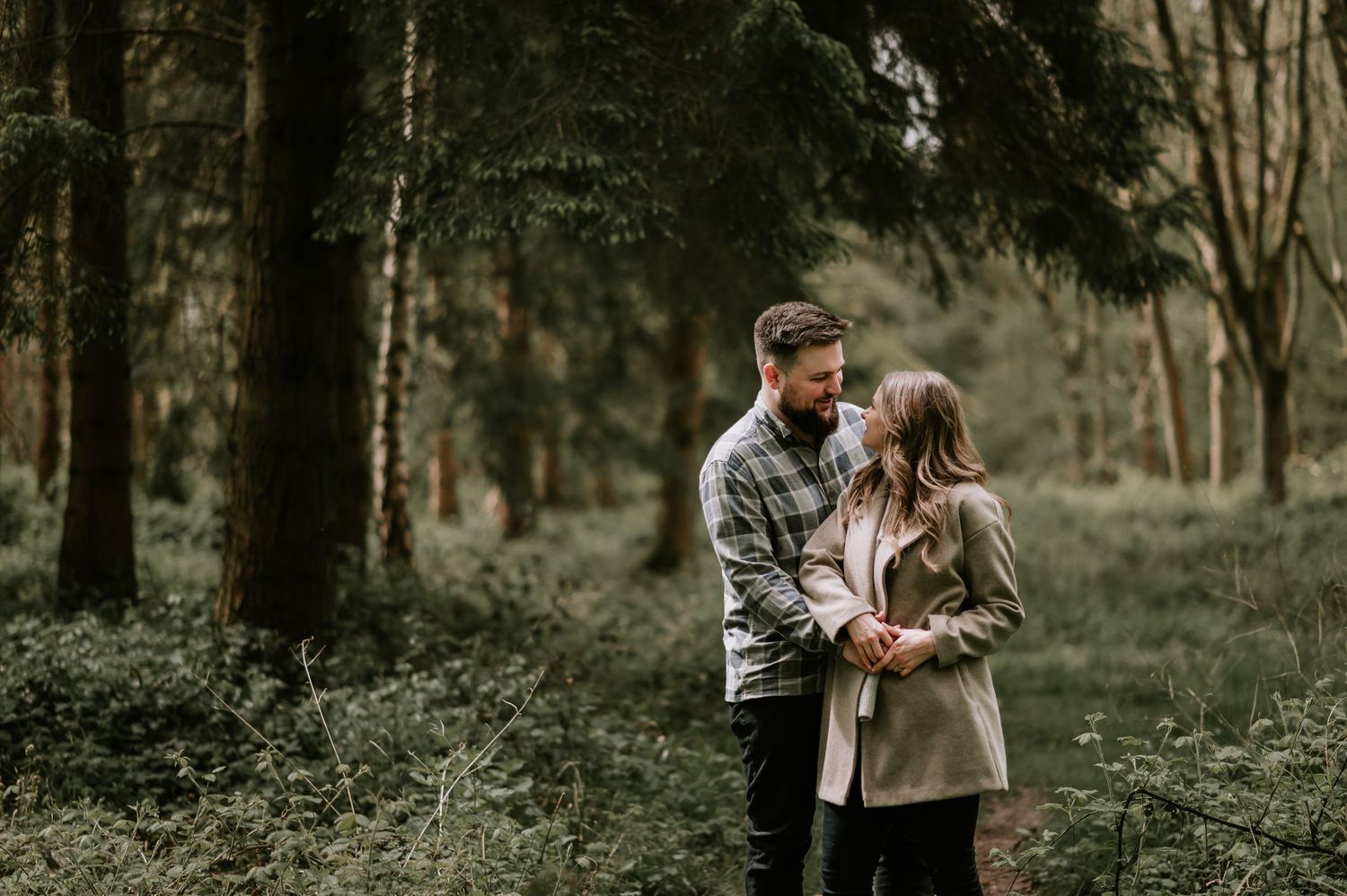 Intimate couple moment captured in misty forest setting.