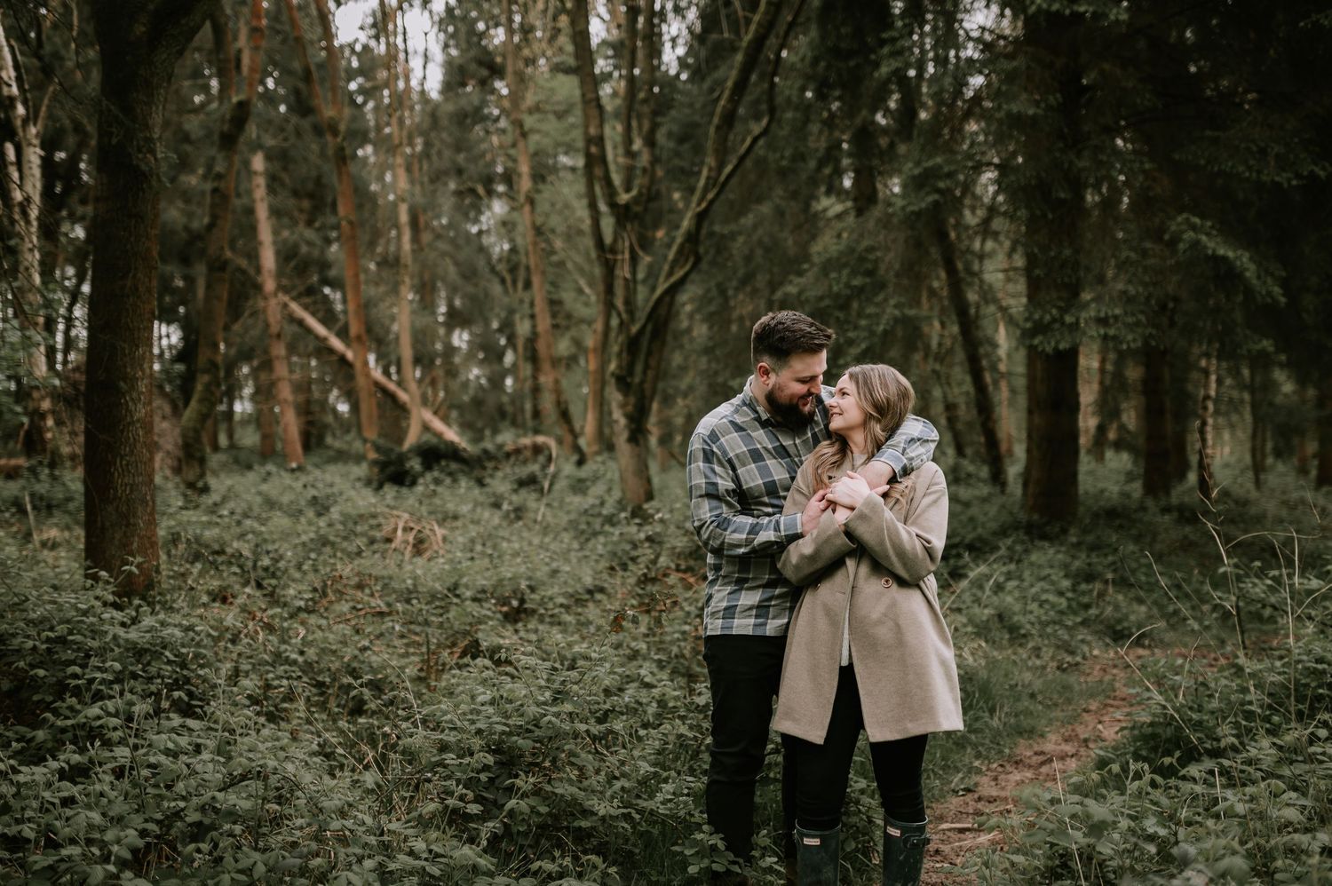 Romantic forest engagement session with couple among trees.