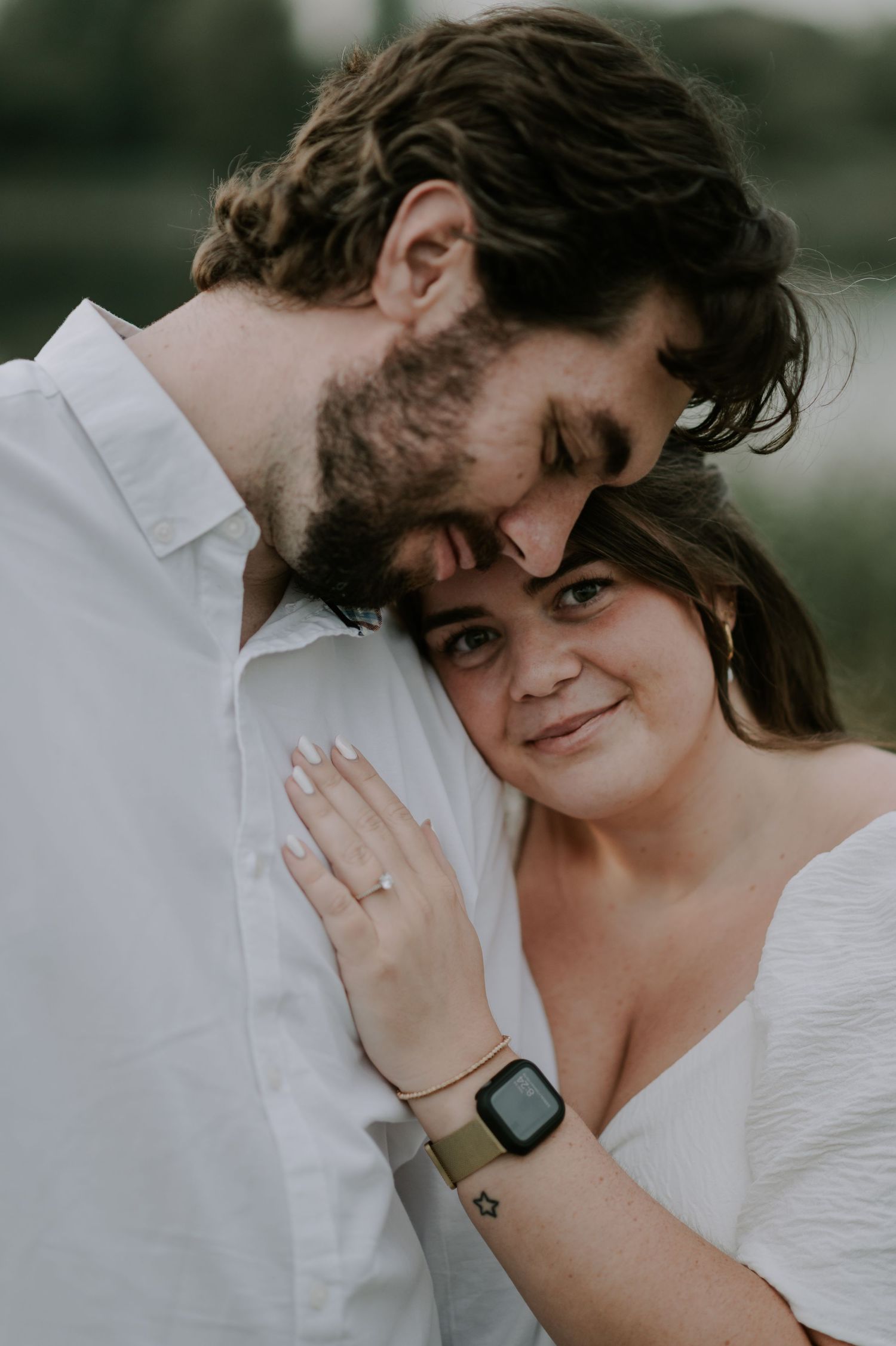 A tender romantic moment shared between a couple in white clothing outdoors.