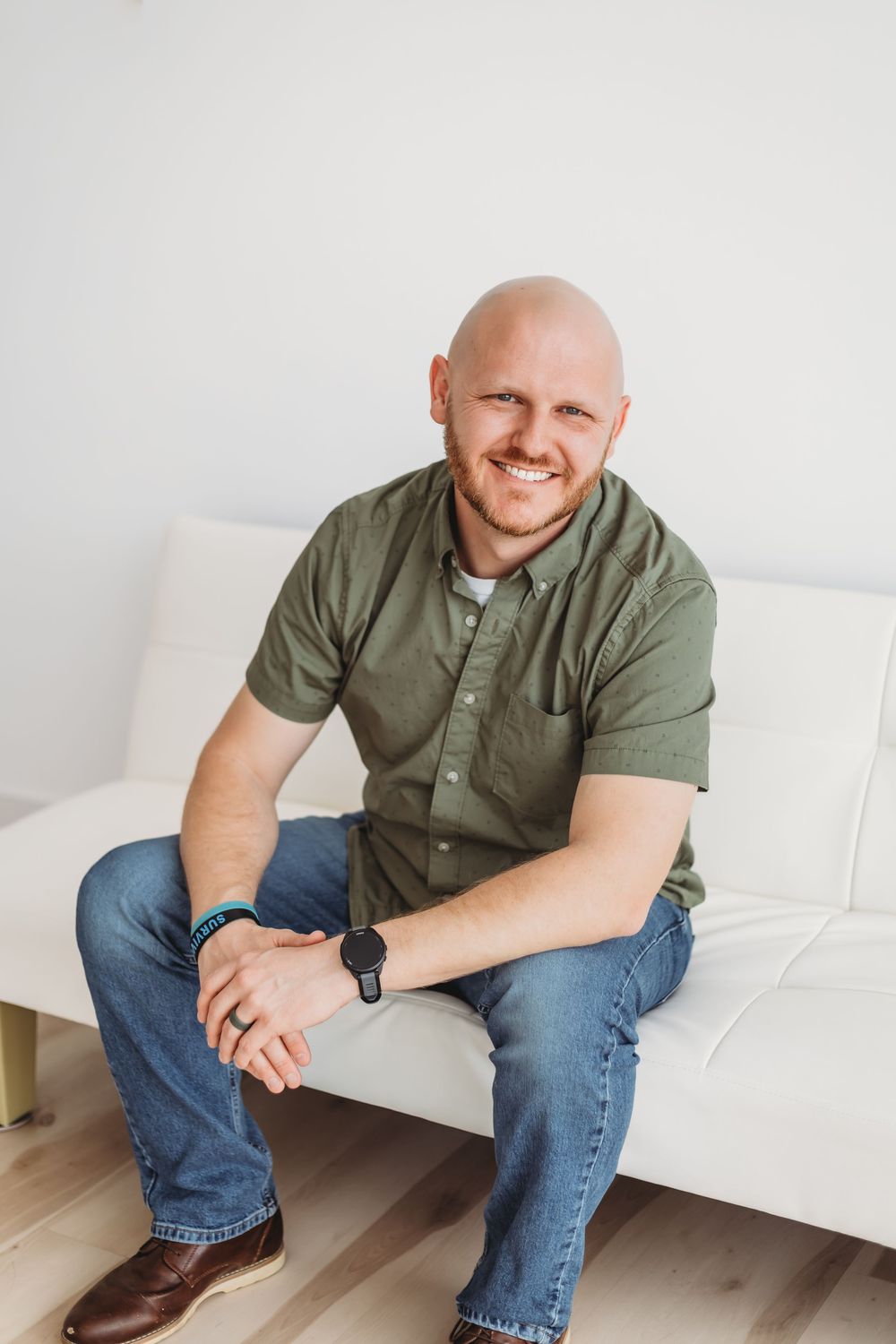 Casual portrait of someone in olive shirt sitting on white couch in bright interior setting Waterbury, CT.