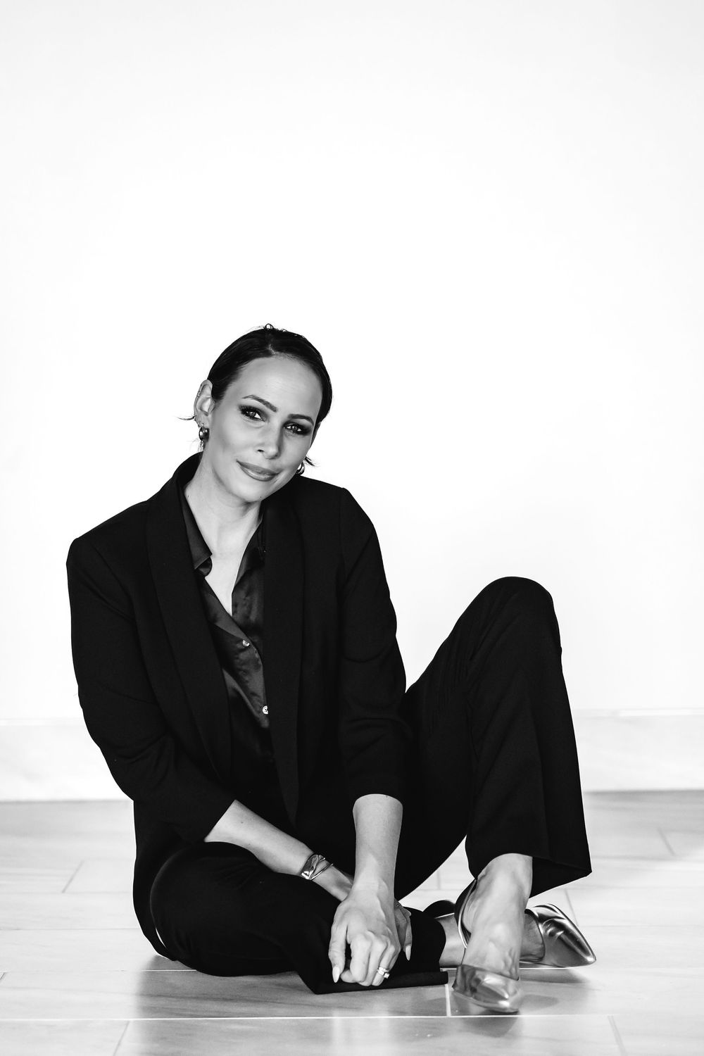 Professional wearing black attire poses elegantly on white floor in artistic portrait series in Hamden, CT.