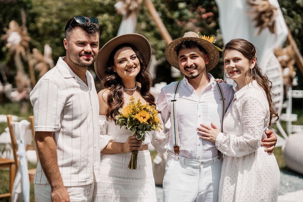 Wedding guests and couple dressed in all white gather for group photos at an outdoor celebration.