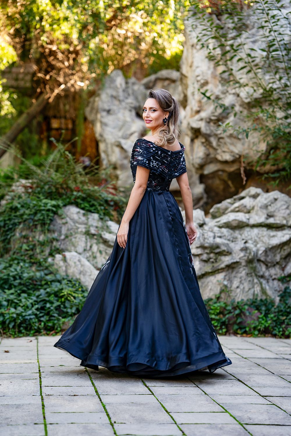 Navy blue ball gown with detailed bodice photographed in garden setting.