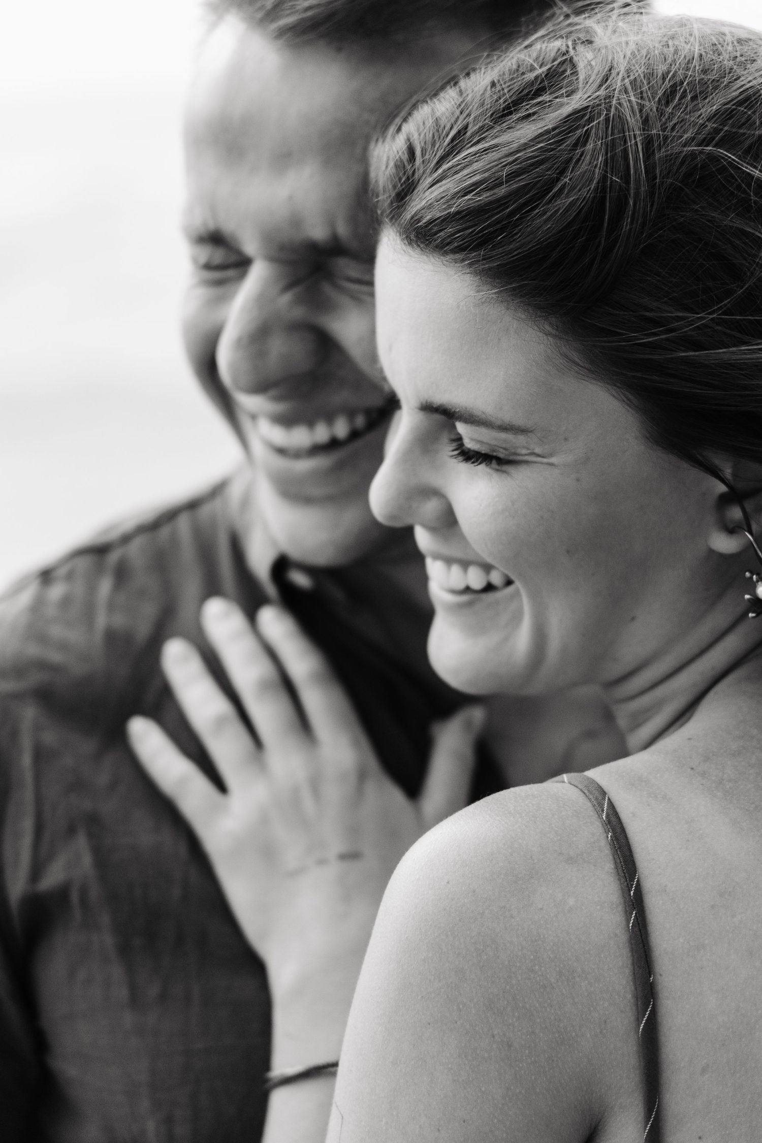 Black and white close-up of a laughing couple sharing a joyful moment together.