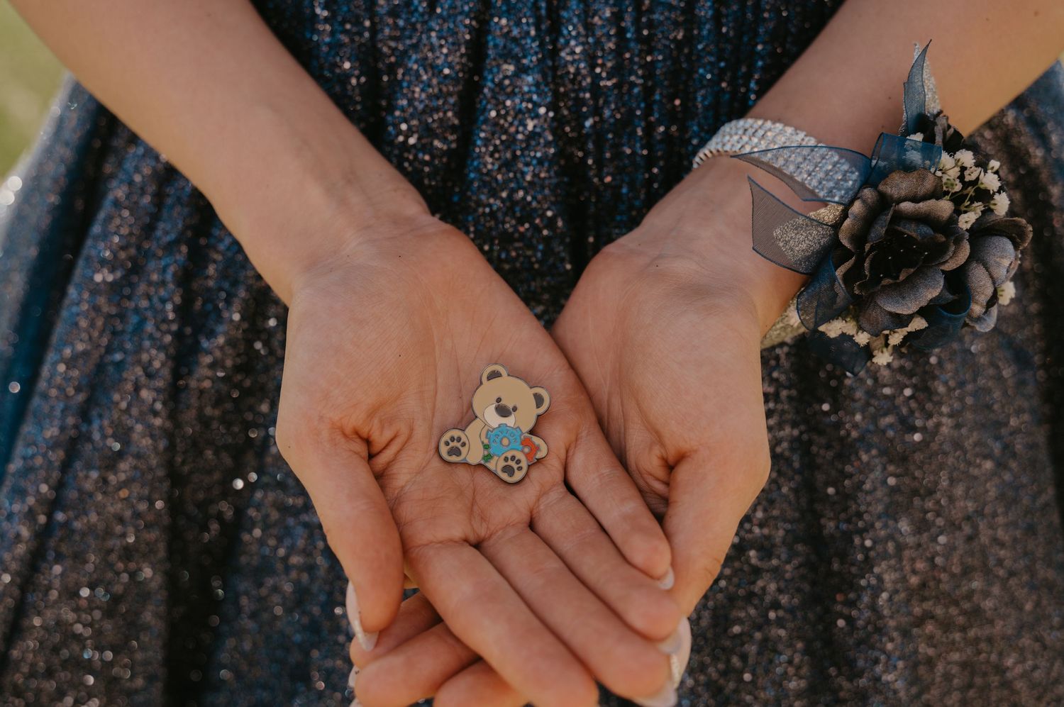 Hands displaying a collection of delicate silver rings with gemstones against a dark textured background.
