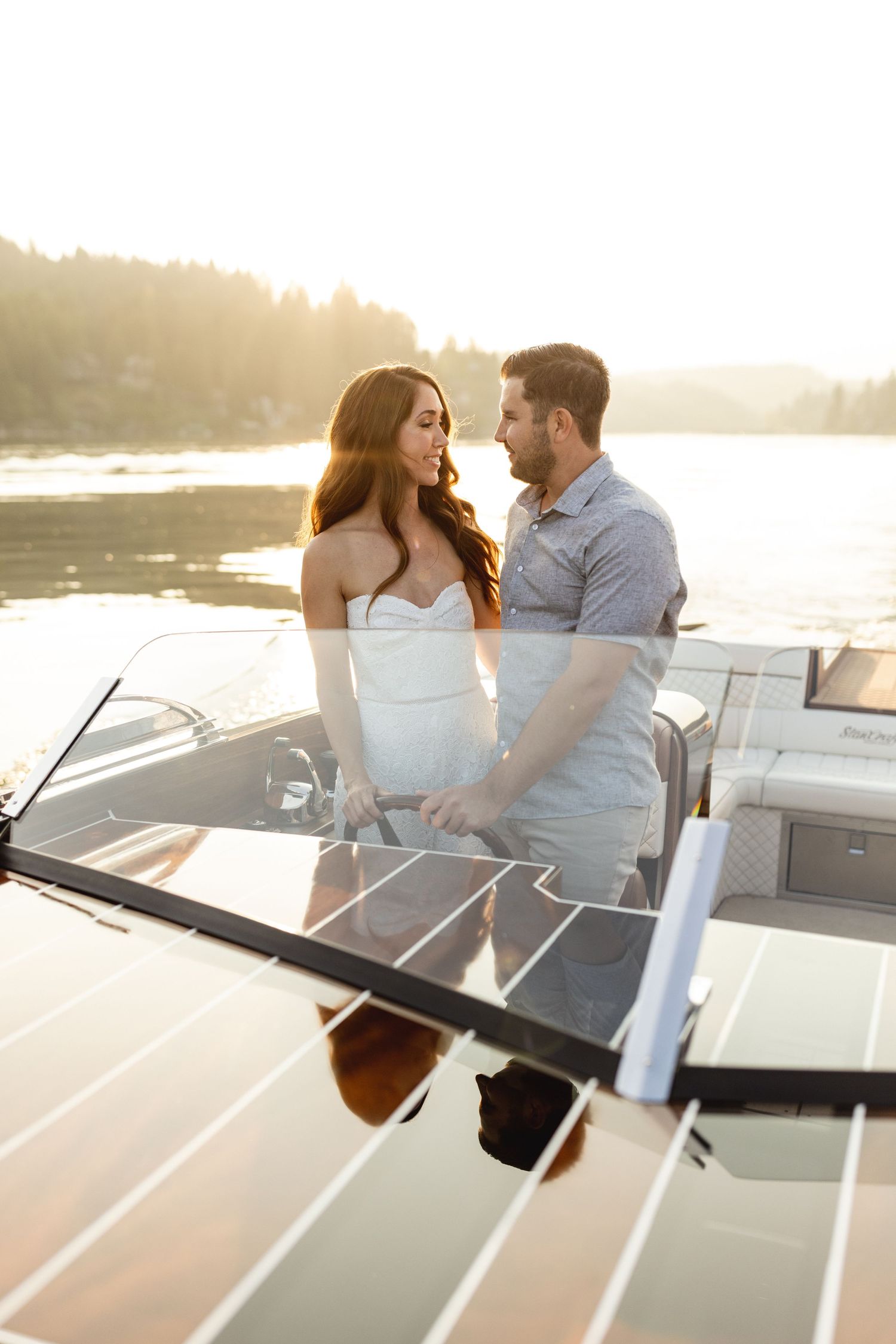 Couple gazes into each other eyes while standing close together on a boat at golden sunset.