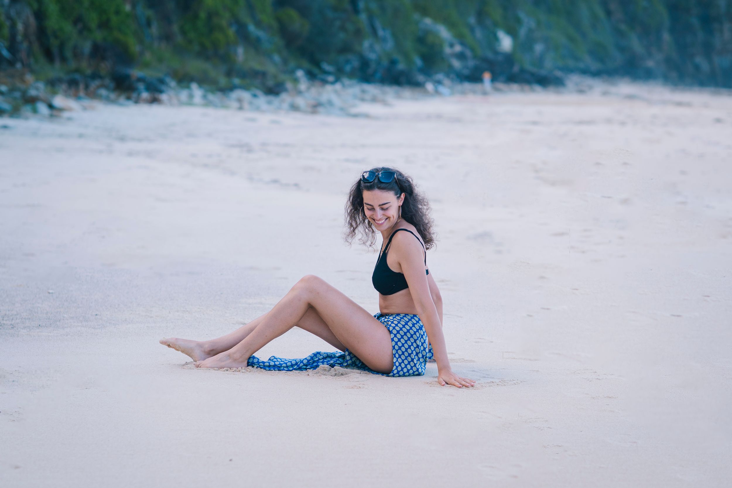 Model posing on a sandy beach during sunset in a stylish swimsuit.