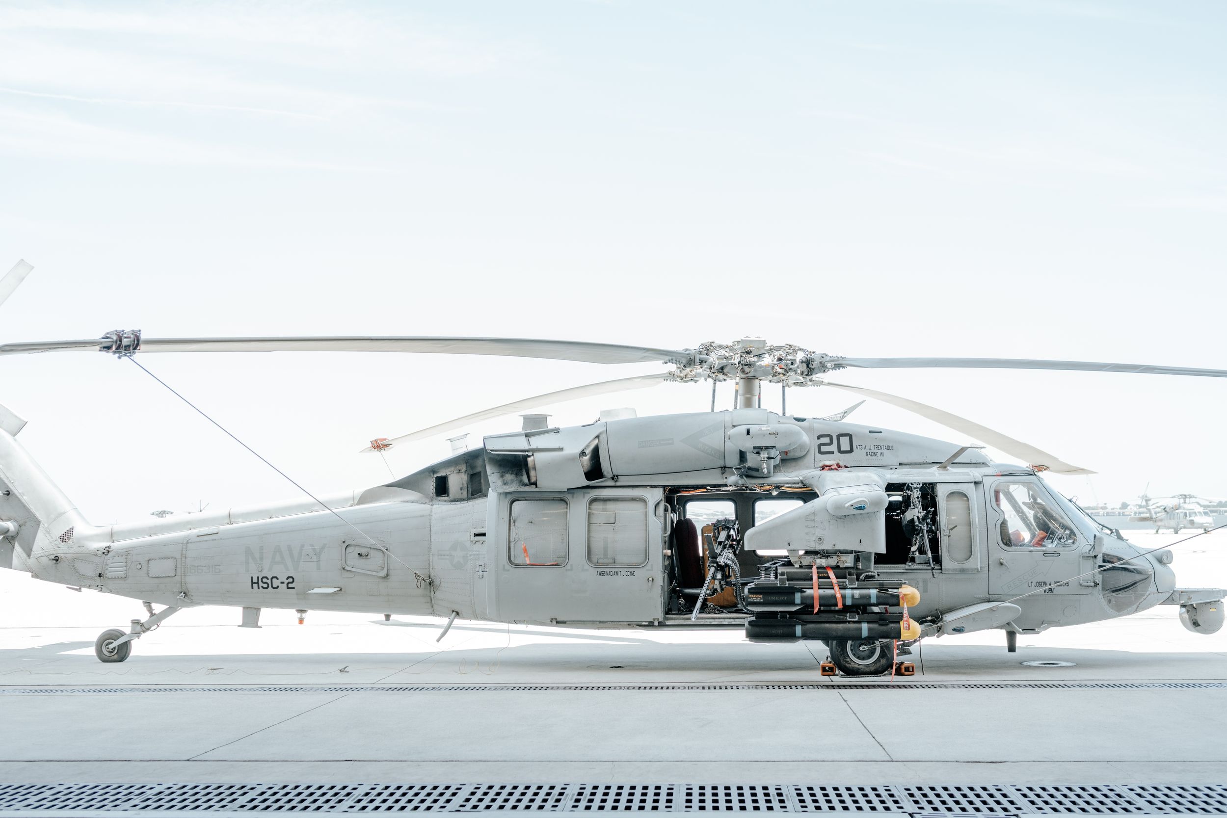 A military Sikorsky UH-60 Black Hawk helicopter sits on a snowy airfield with its side door open.