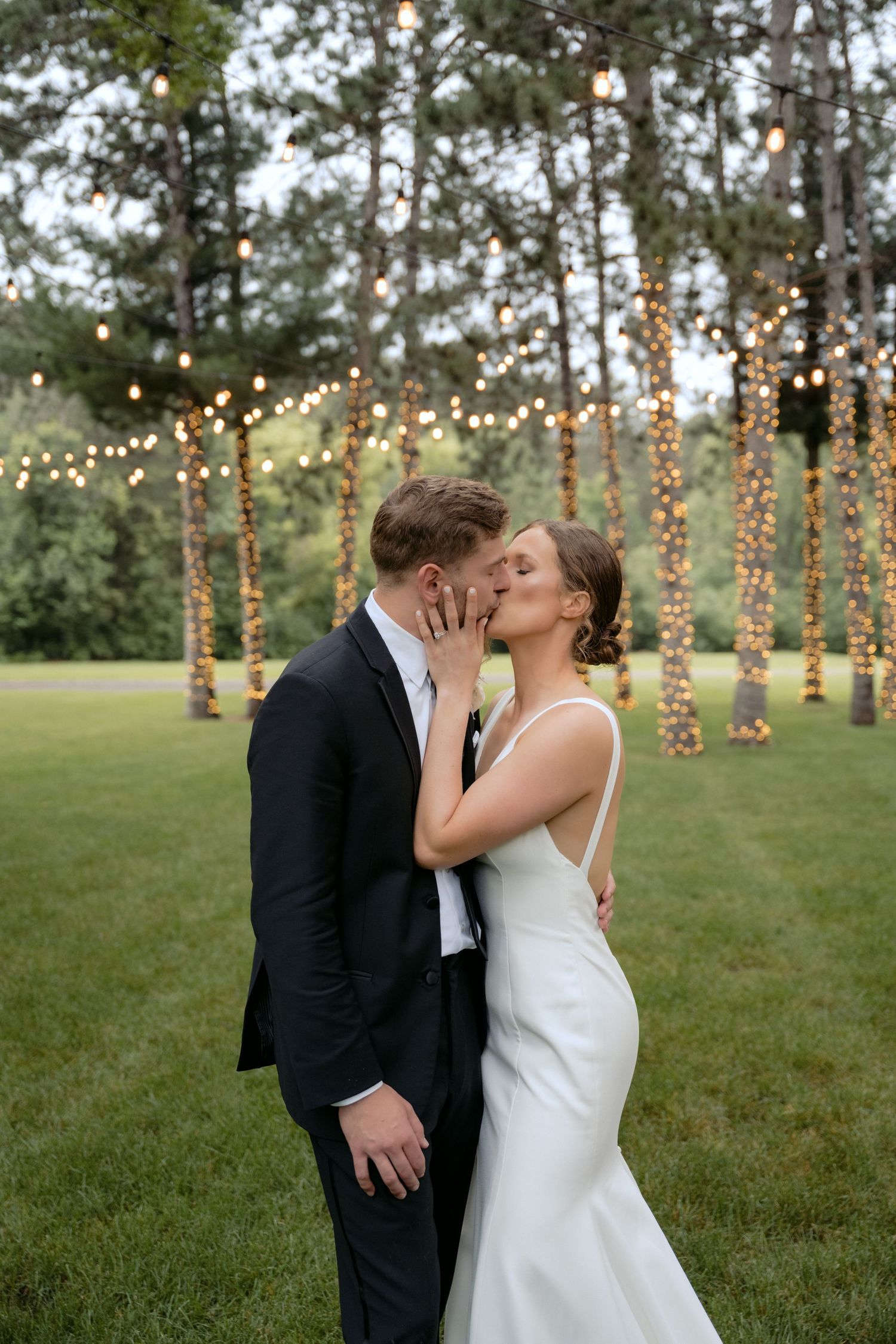 Bride and groom kissing surrounded by twinkle lights during wedding photography at La Pointe Events in Somerset, Wisconsin