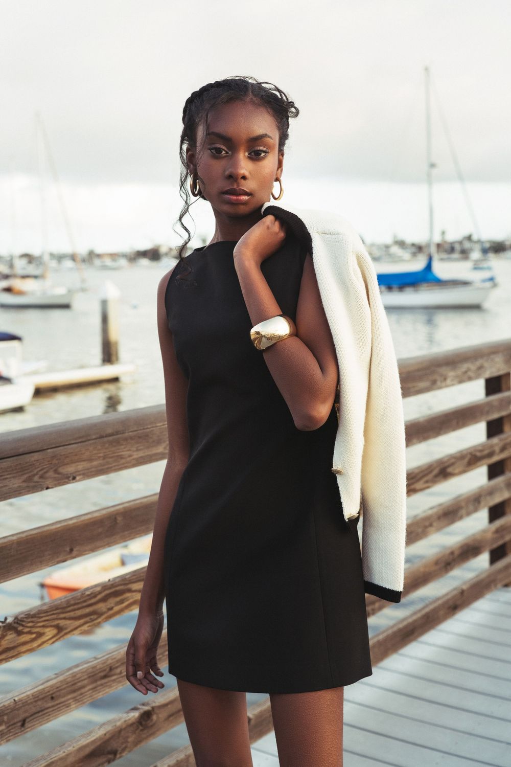 Black fashion model standing with sweater over shoulder at coastal harbor, Atlanta editorial portrait and fashion photographer