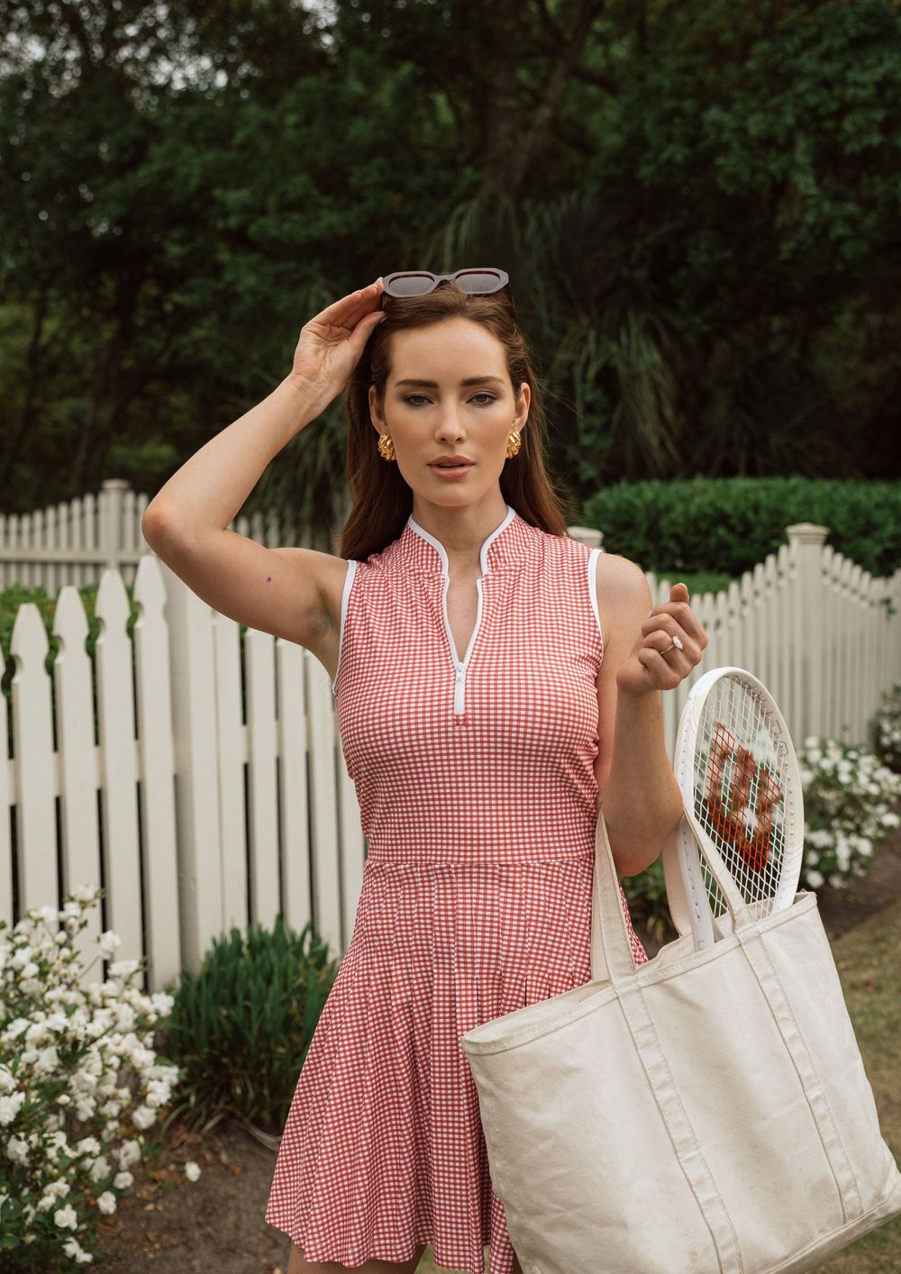 Model Chandler Bailey wears red gingham tennis dress in front of white picket fence, Atlanta editorial portrait and fashion photographer