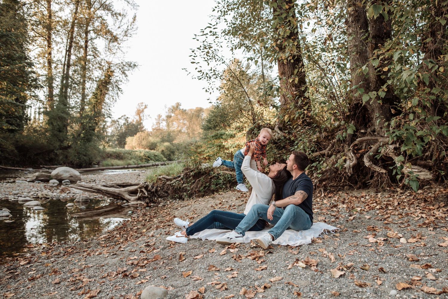 A couple shares an intimate moment while sitting on rocks by a stream.