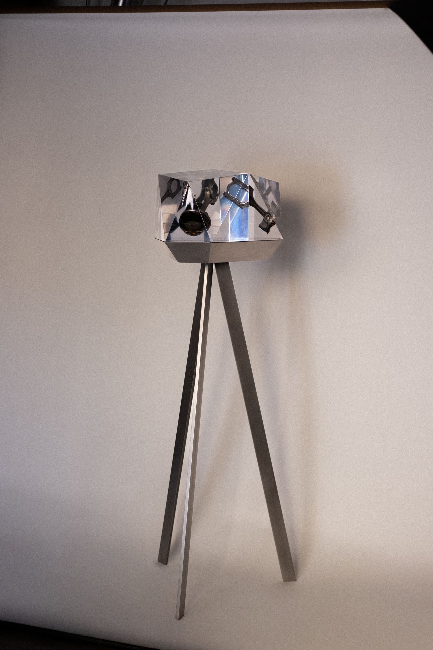 Close-up of a modern transparent glass lamp with a dark oval opening, minimalist design against a neutral background.