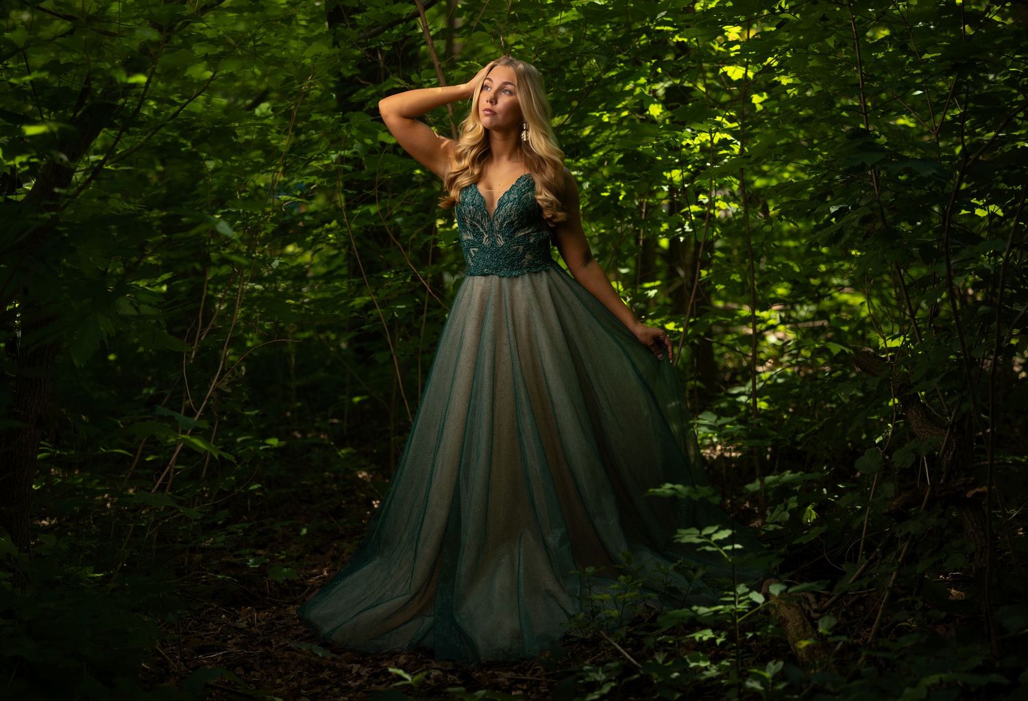 Fairytale-inspired senior portrait of a girl in a green gown photographed in the woods