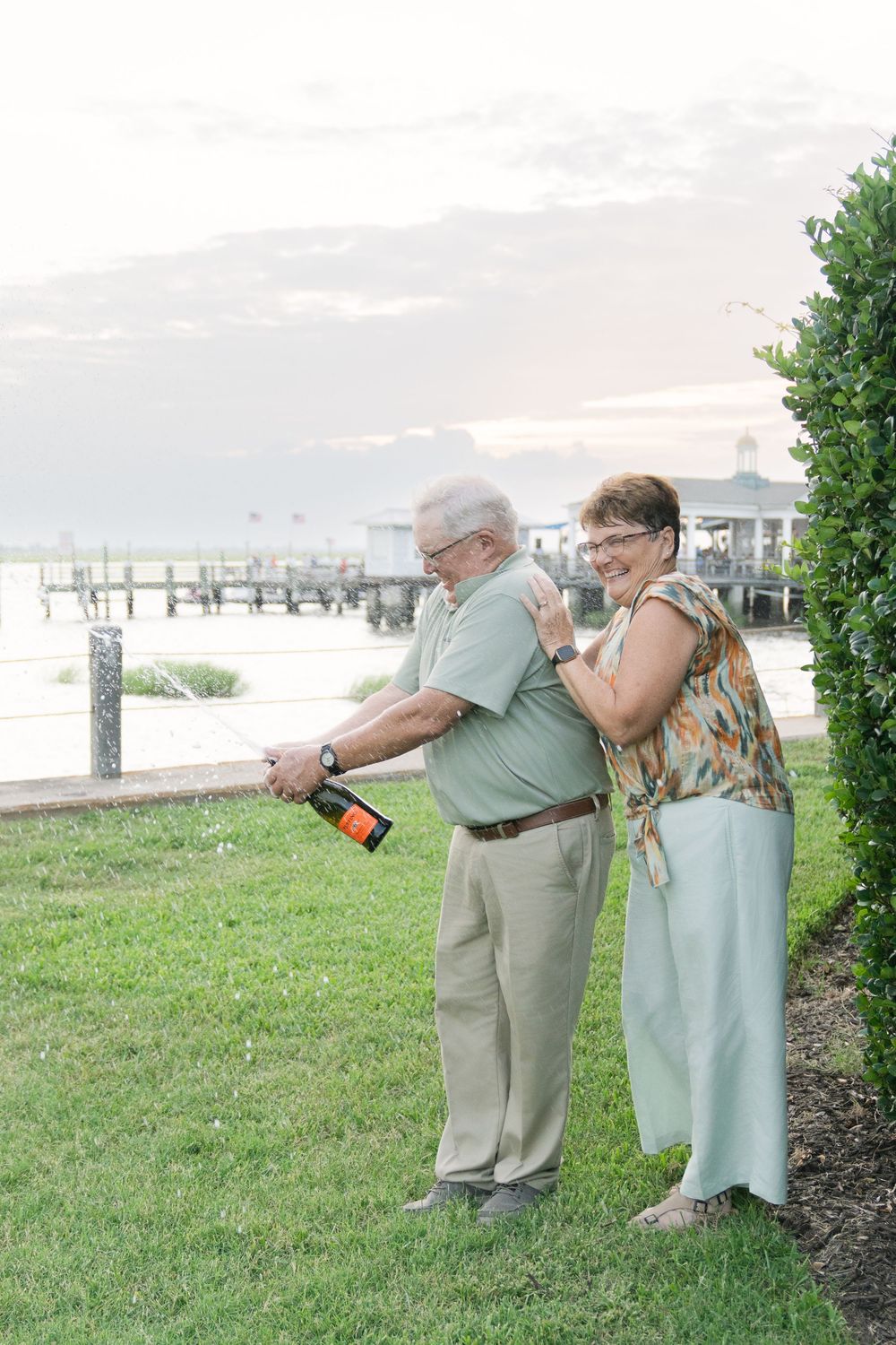 Lori and Kenny smile together near the waterfront for their beach coastal anniversary portraits