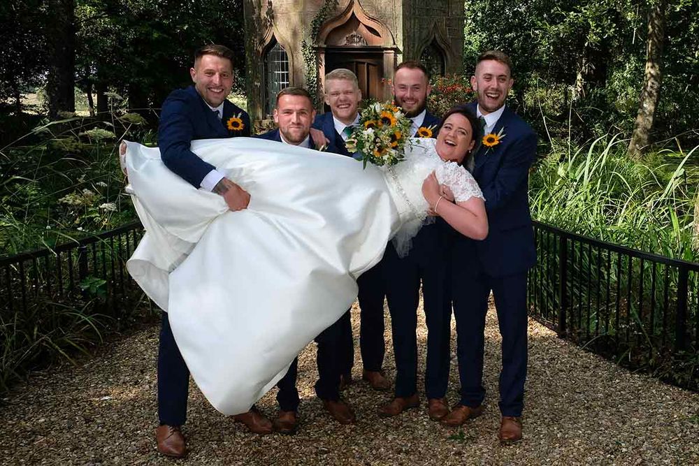 Bride lifted by groomsmen in navy suits at Blaithwaite House wedding venue near Wigton Cumbria