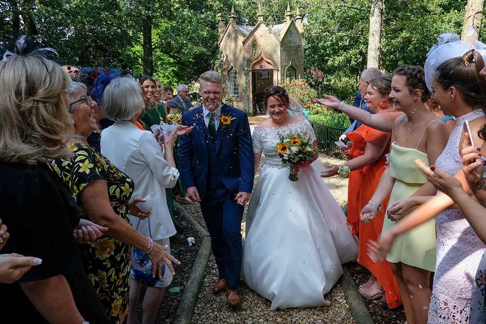Bride and groom walk through cheering guests and bridesmaids after their outdoor wedding at glorious Blaithwaite House Wigton