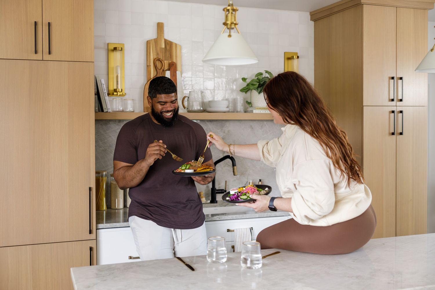 Seattle meal prep service product photo of lifestyle active couple eating meal together in kitchen woman sitting on counter man standing