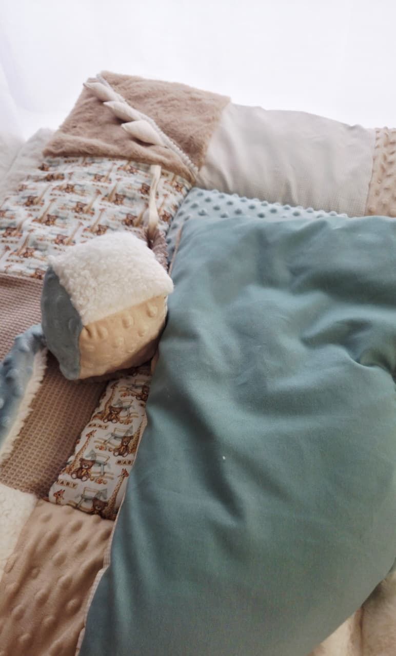 Soft baby quilt with patchwork design in beige and teal tones, featuring a plush cube toy and minky fabric blanket.