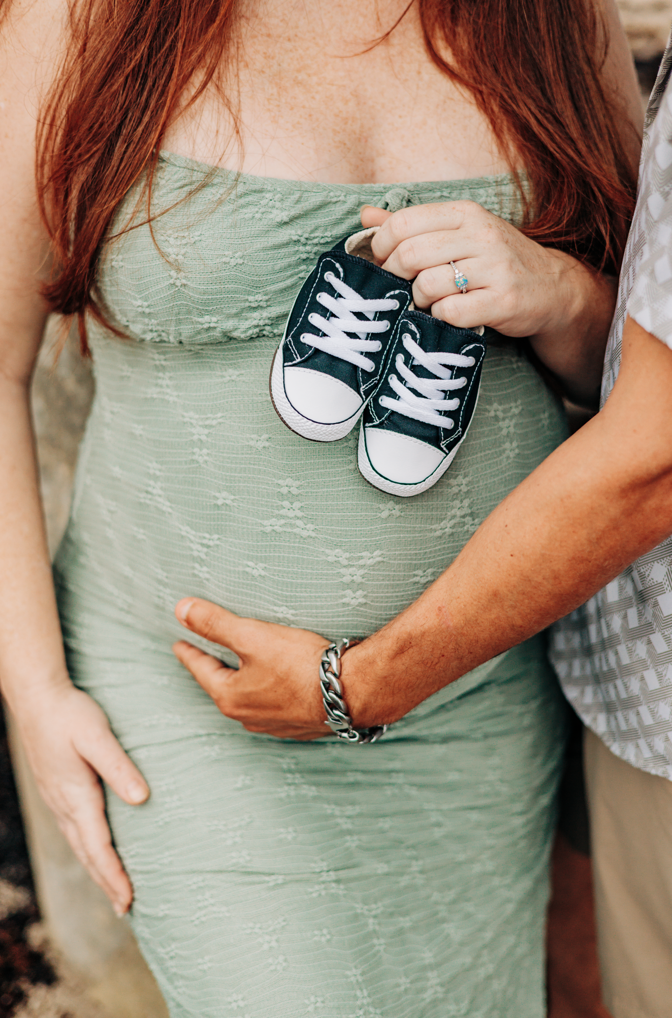 Maternity photographer Palm Beach County detail of parents holding tiny baby shoes during their Coral Cove Beach session in Jupiter
