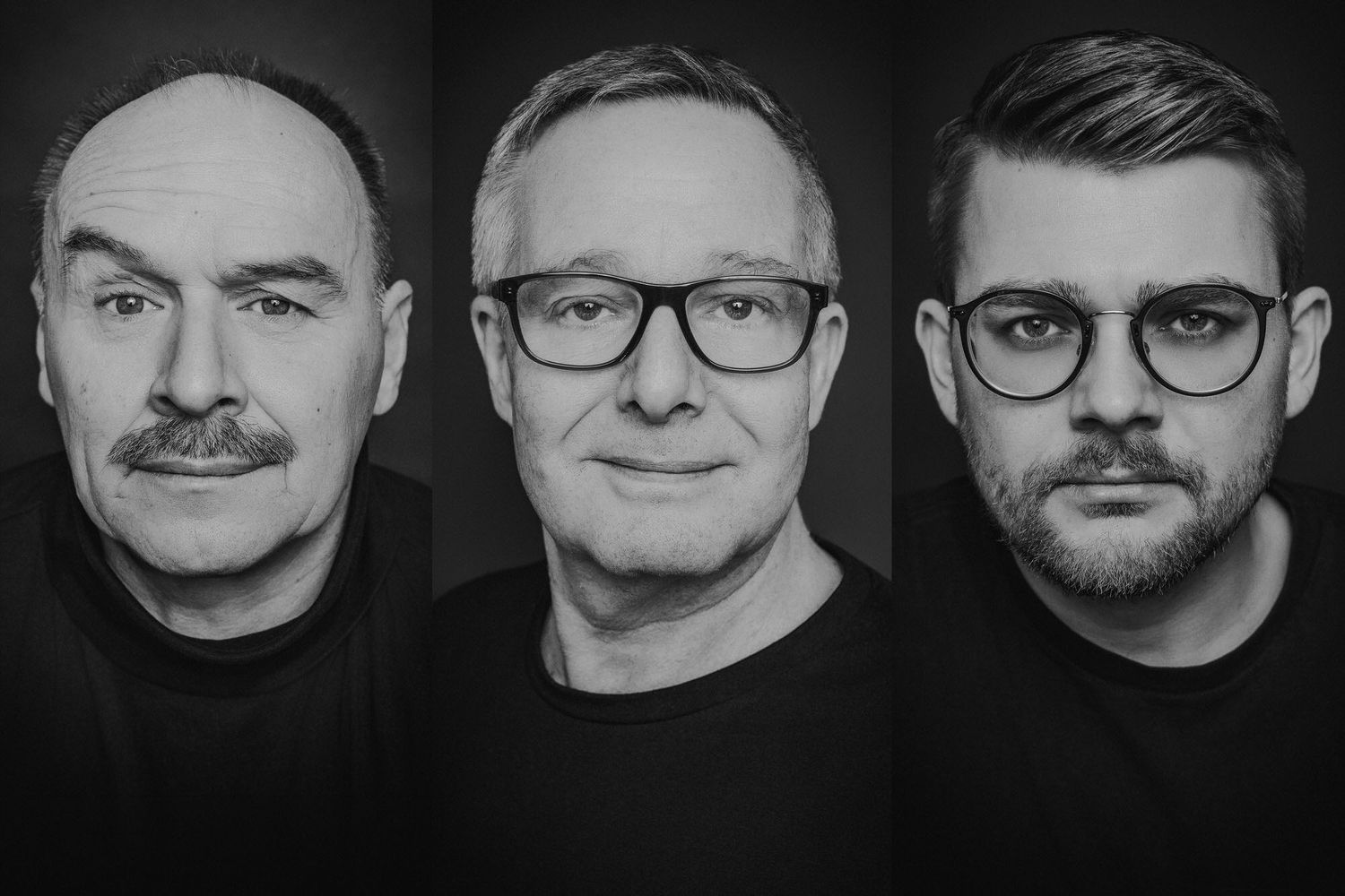 Black and white portrait of three men, two older with mustaches and one younger, all wearing glasses and black shirts.