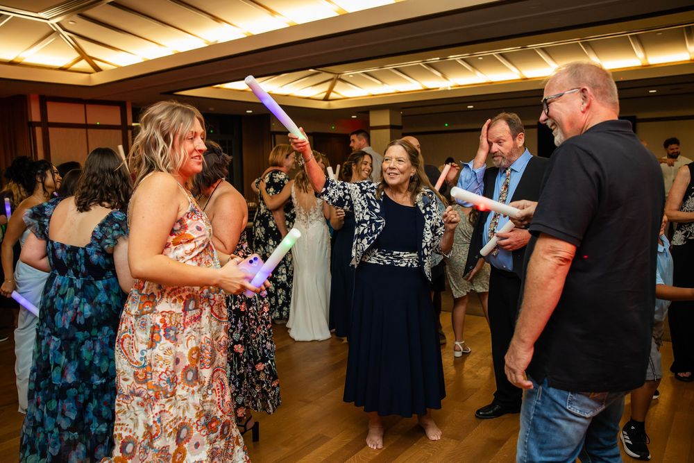 Guests dancing with glow sticks at an elegant indoor wedding reception celebration.