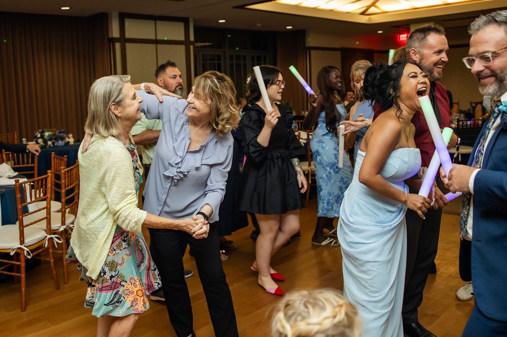 Guests dancing and celebrating with glow sticks at a lively wedding reception in an elegant ballroom.