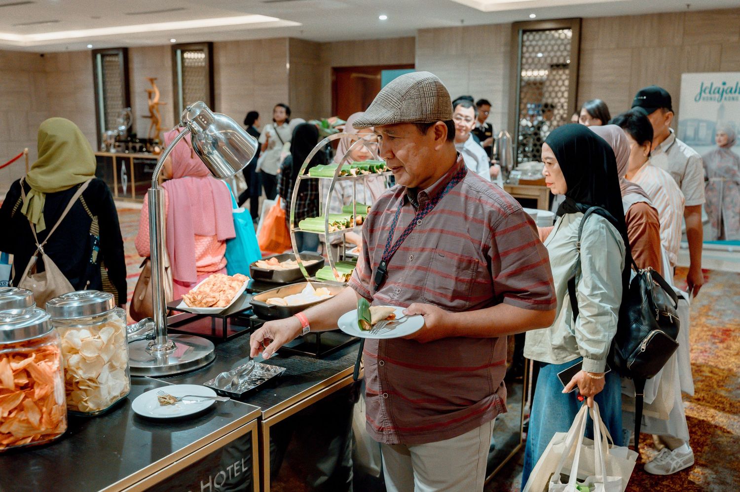 Guests serving themselves at an elegant hotel buffet spread during a busy catered event or conference.