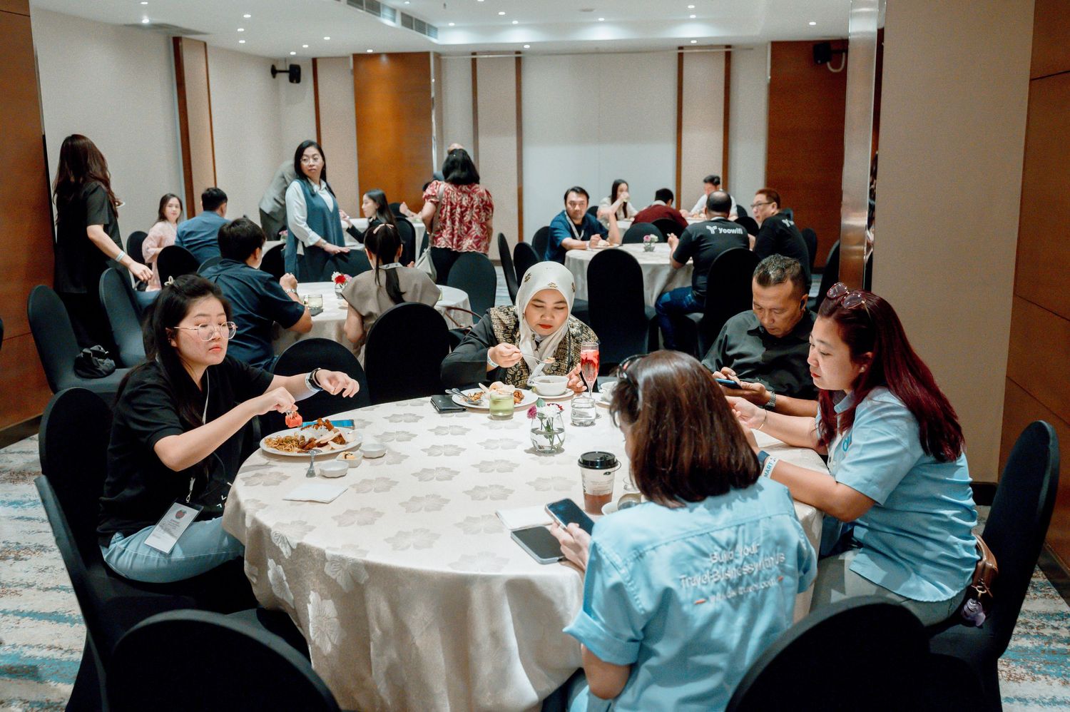 Group of professionals networking at a formal dinner event, seated at round tables in a conference banquet hall.