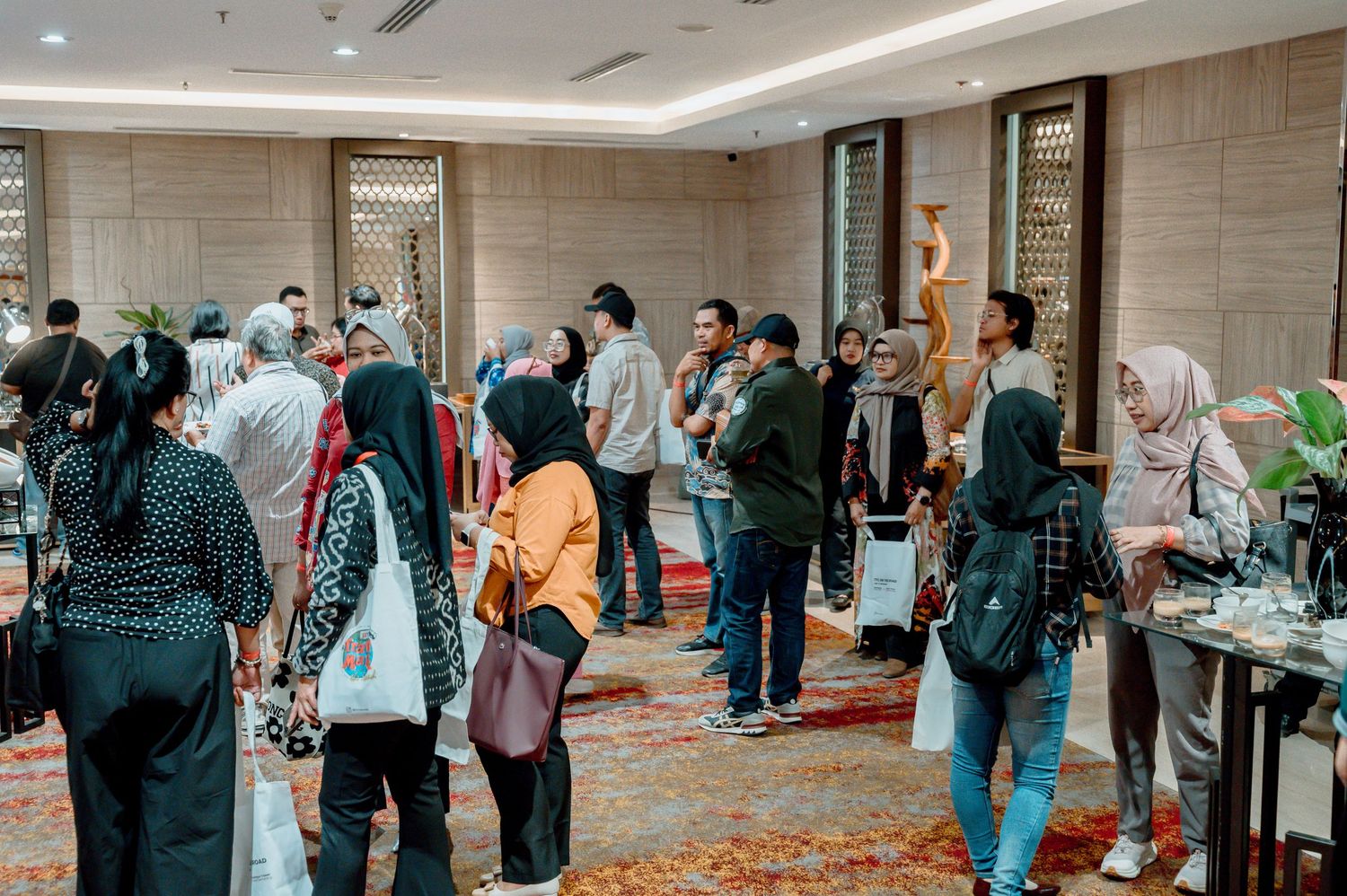 Diverse group of people networking at an indoor corporate event in a modern hotel ballroom.