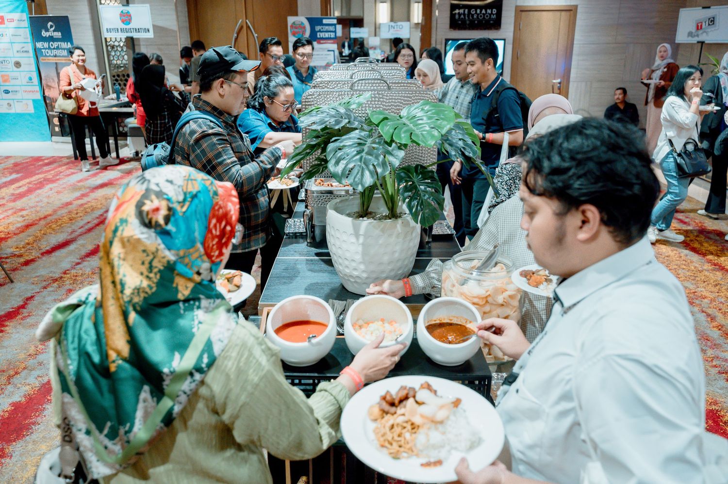Guests serving themselves at a buffet spread during a corporate conference event in a decorated banquet hall.