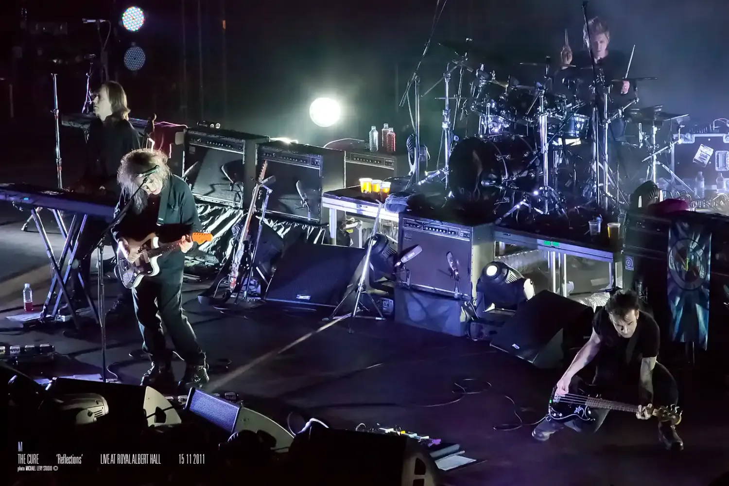 Rock band performs energetically on stage with dramatic lighting and equipment.