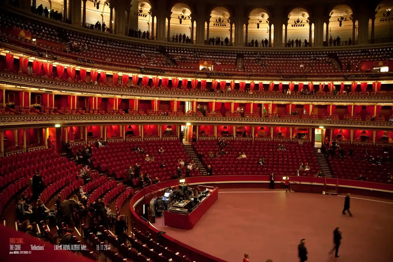 Interior view of the Royal Albert Hall in London, featuring red tiered seating and ornate balconies.