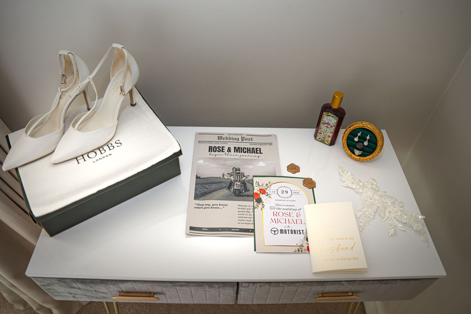 White bridal heels in Hobbs box on dresser with wedding newspaper, gold bottle, and decorative items for brides wedding day, Yorkshire