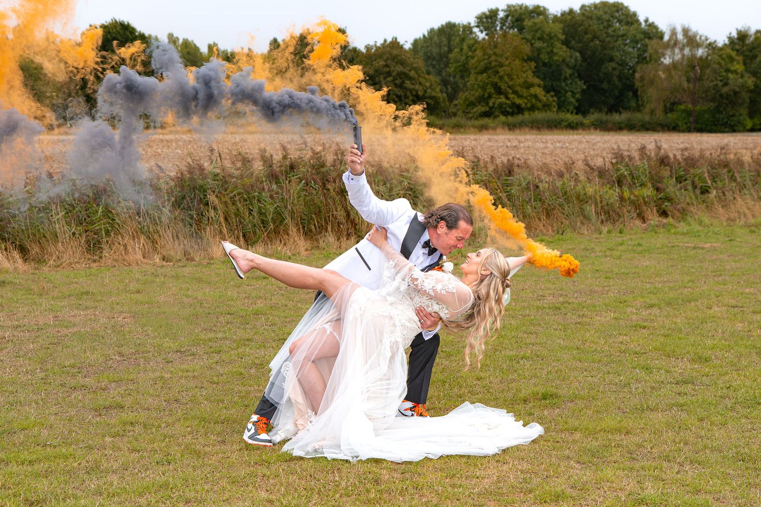 Bride and groom kissing in a dip pose outdoors with dramatic orange smoke bombs filling the sky behind them.Yorkshire, Sheffield, UK, Leeds