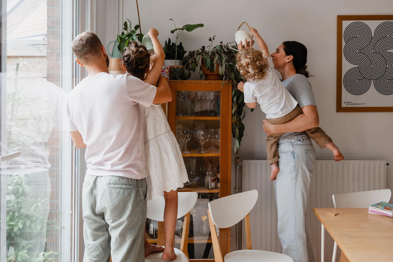Reportage photo famille a domicile pres de Lille, arrosage des plantes, un rituel du quotidien capture en lumiere naturelle