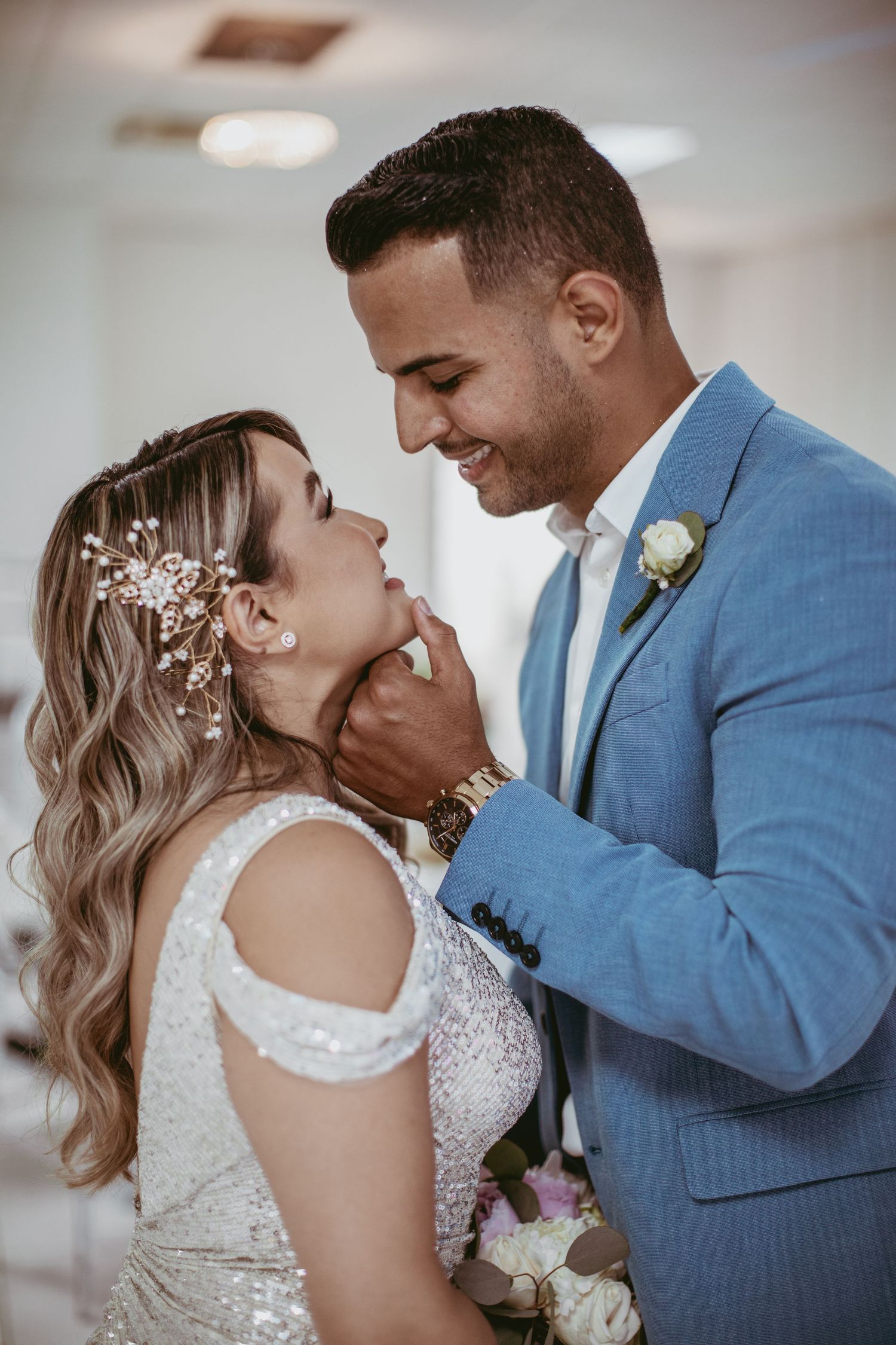 Intimate moment between newlyweds in formal attire sharing loving gesture.