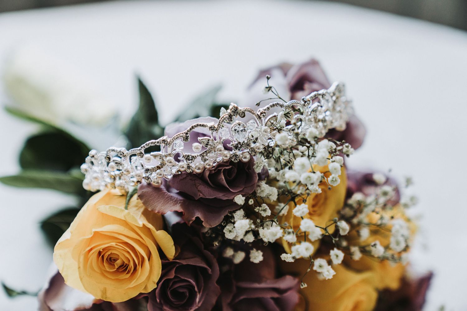 Close-up of wedding bouquet featuring yellow roses and purple flowers with baby's breath.