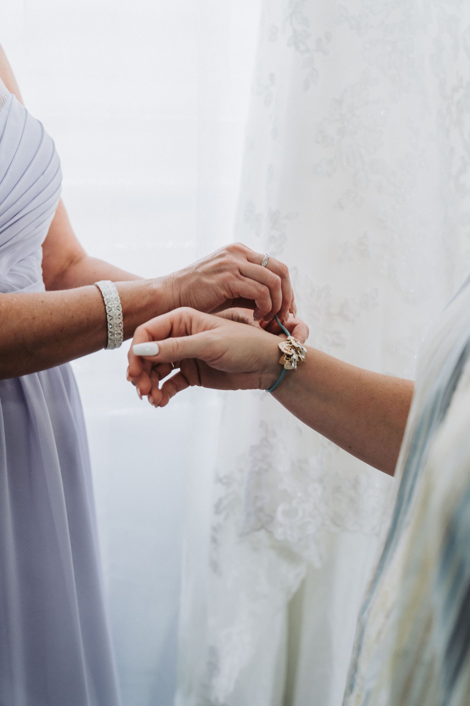 Bridesmaid helping with bracelet or jewelry before wedding ceremony.