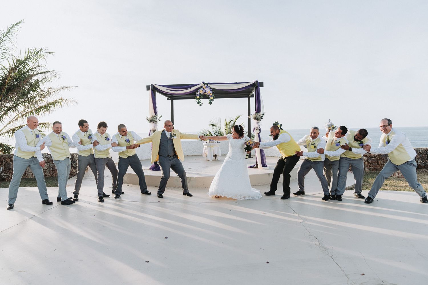 Fun wedding photo with groomsmen and bridesmaids posing in choreographed dance move formation.