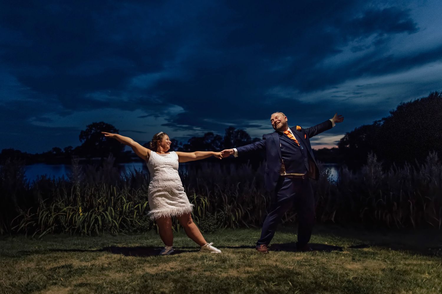 Bride and groom enjoying an evening portrait by the lake at Sandhole Oak Barn wedding venue in Cheshire.