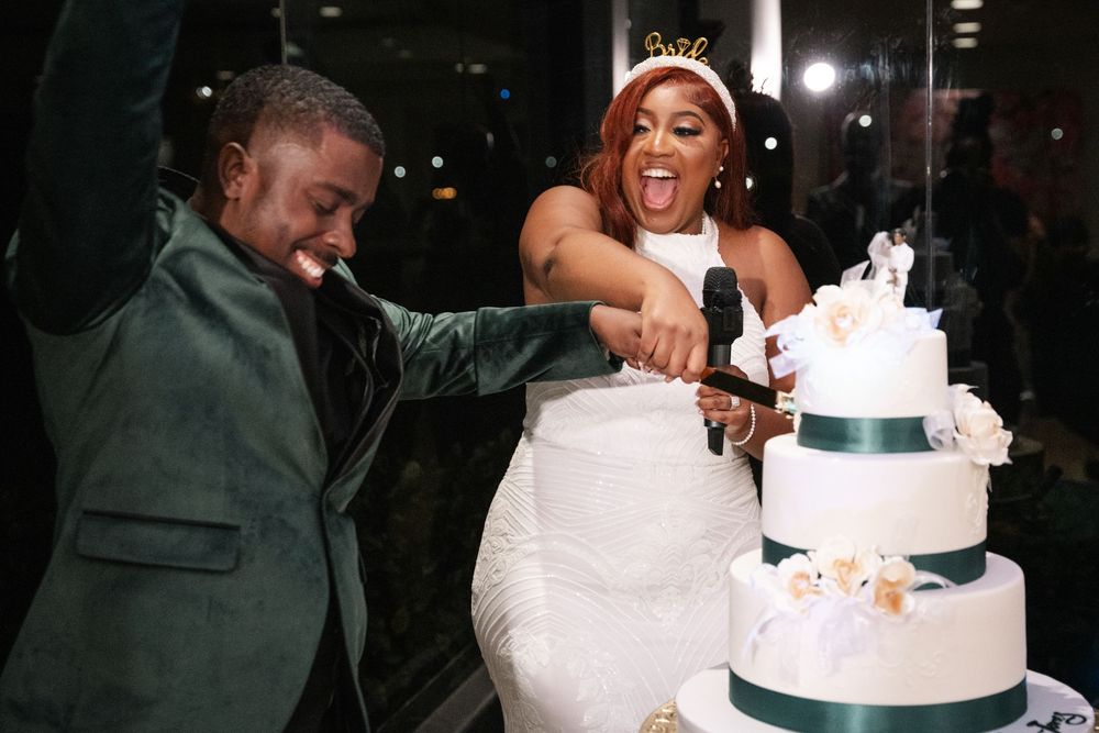 Bride and groom cutting a white tiered wedding cake together at their wedding reception celebration.
