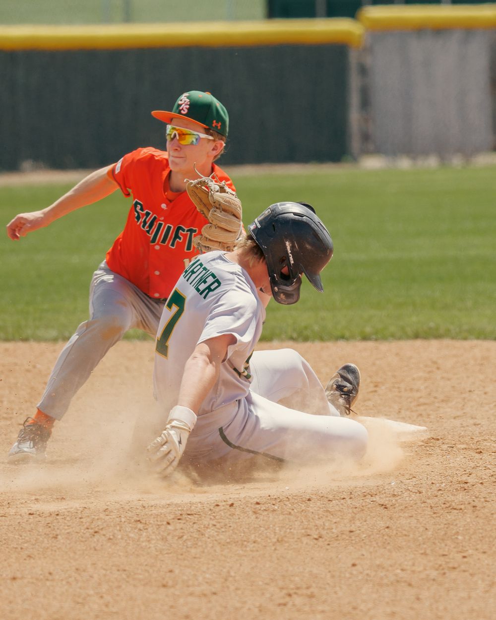 A baserunner slides into second base as an orange-uniformed infielder attempts a tag.