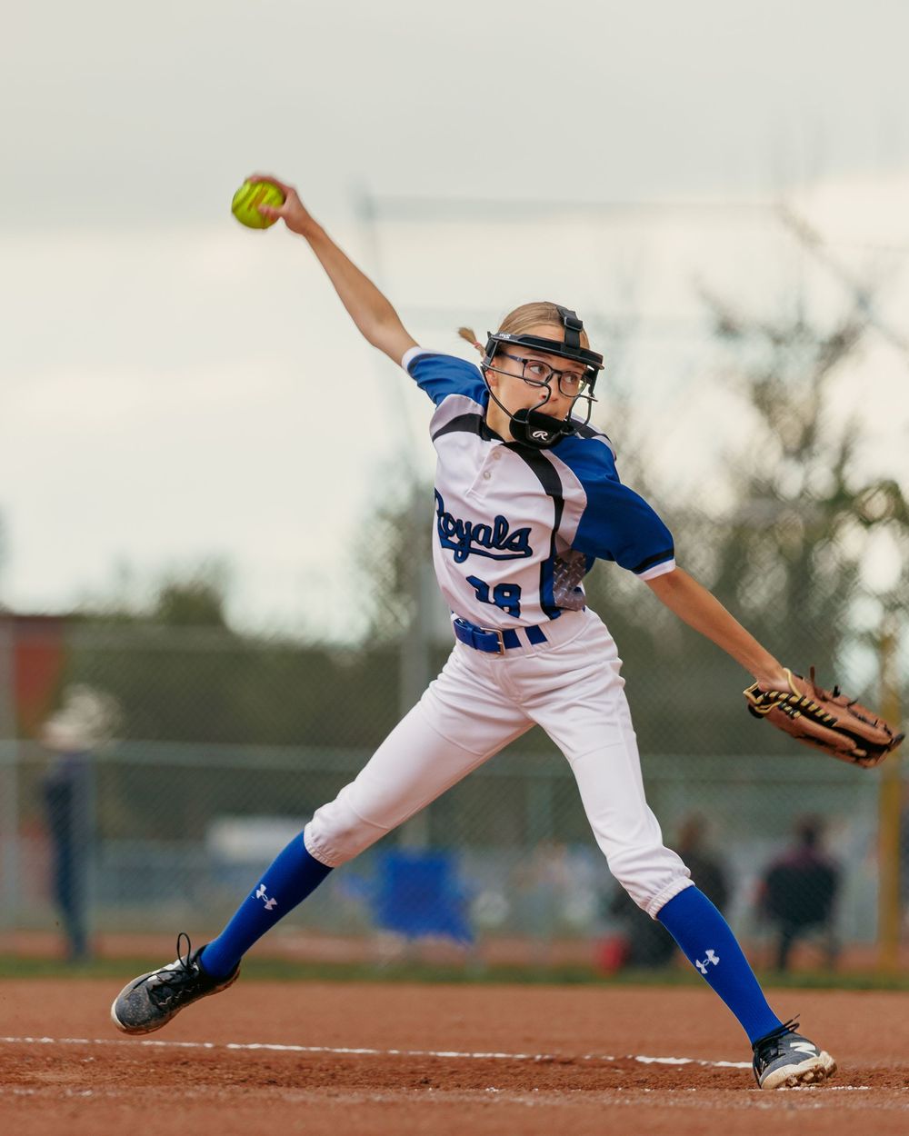 A Royals softball pitcher winds up to throw during a competitive game.