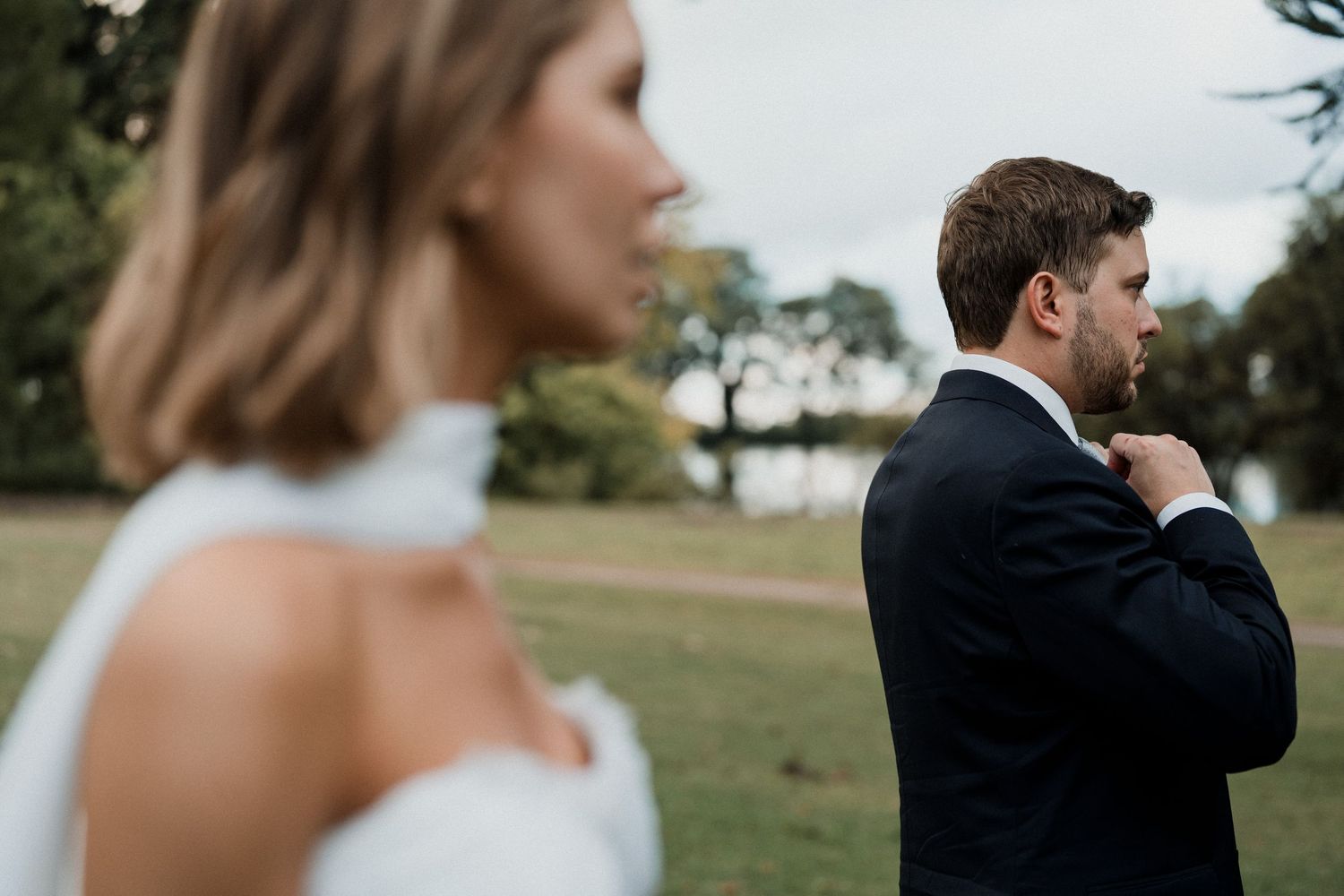 Intimate wedding portrait of newlyweds embracing on manicured lawn during golden hour.