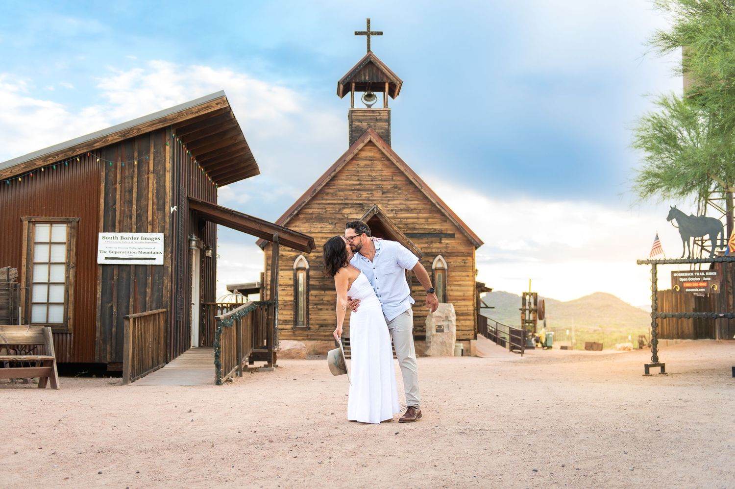 A couple poses at Goldfield Ghost Town church at sunrise as their celebrate their anniversary with a Arizona family vacation photo session.