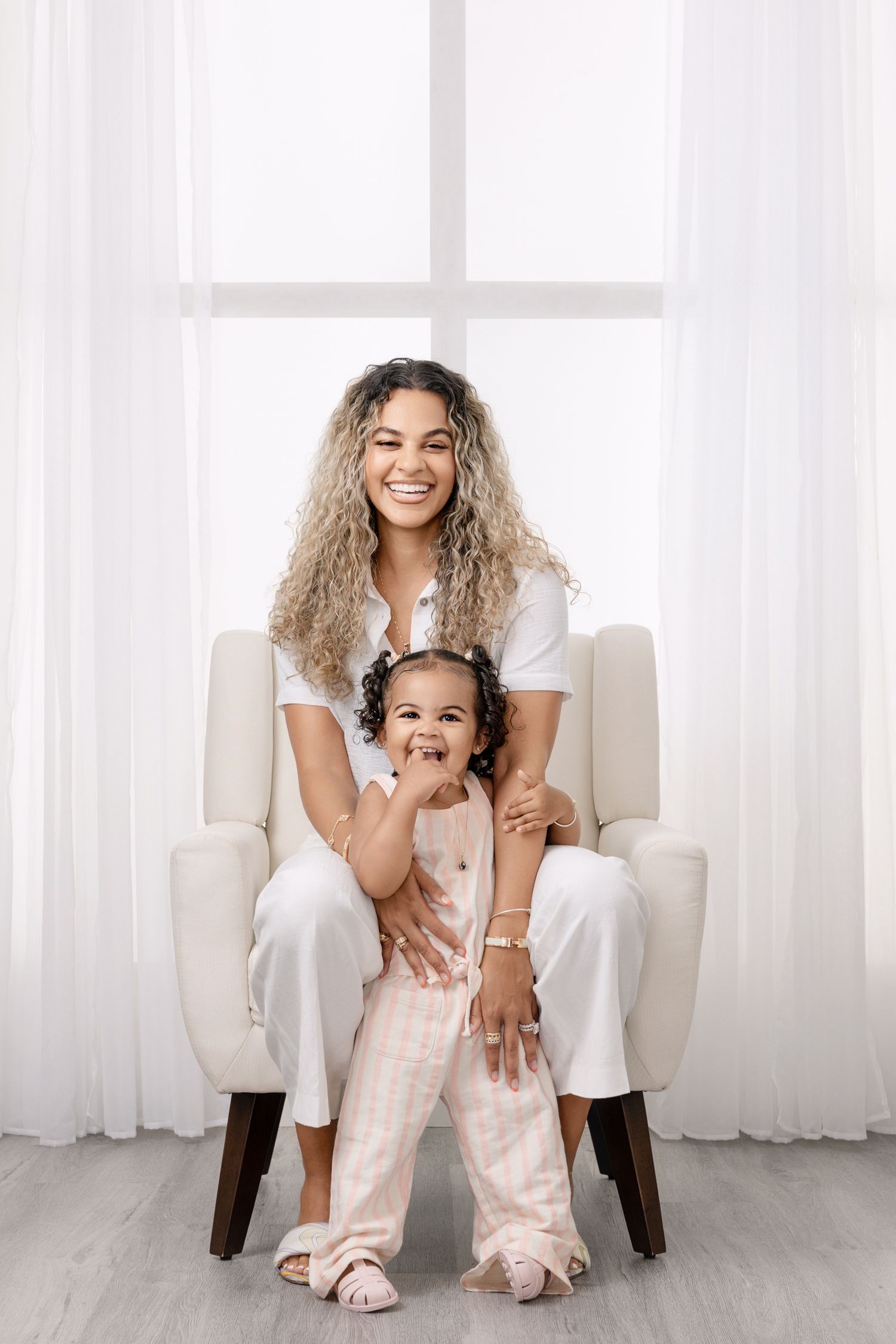 Mother smiling with her young daughter in a bright studio portrait