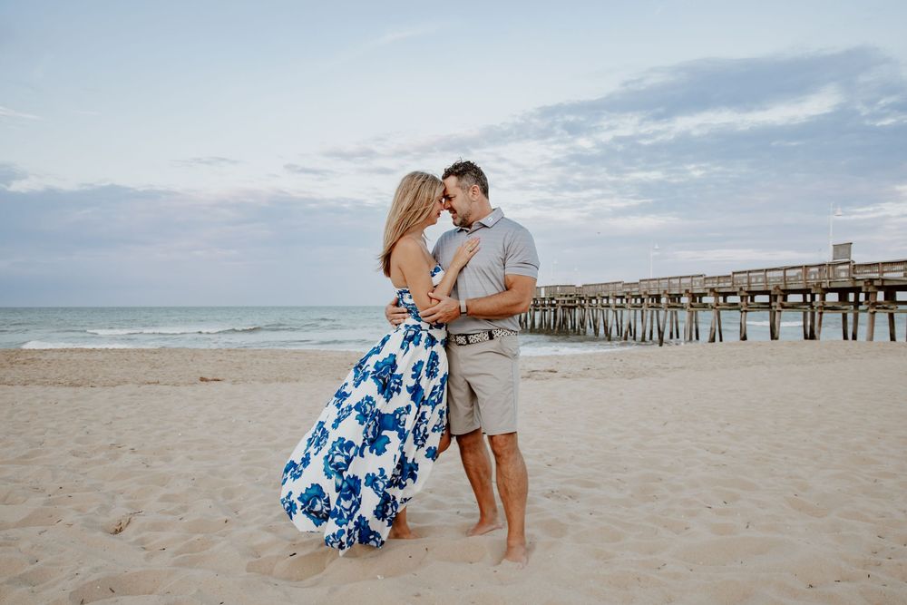 Romantic couple embracing on sandy beach in front of ocean pier at dusk. Sandbridge.