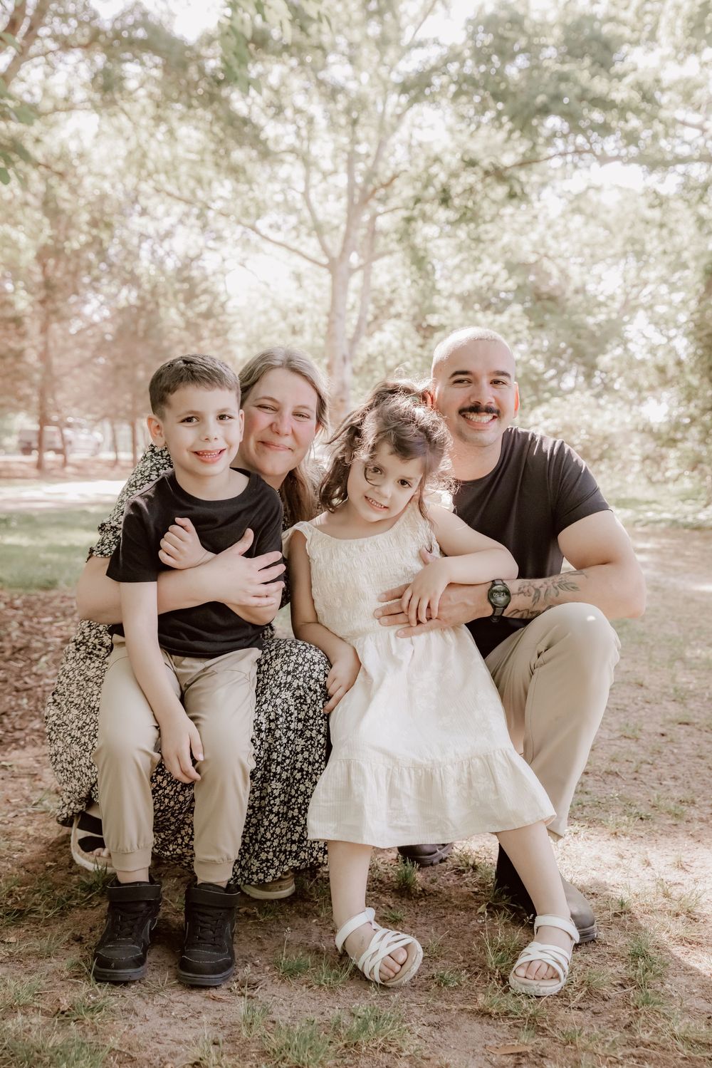 Happy family of four with two young children smile together during outdoor park portrait session. Yorktown.