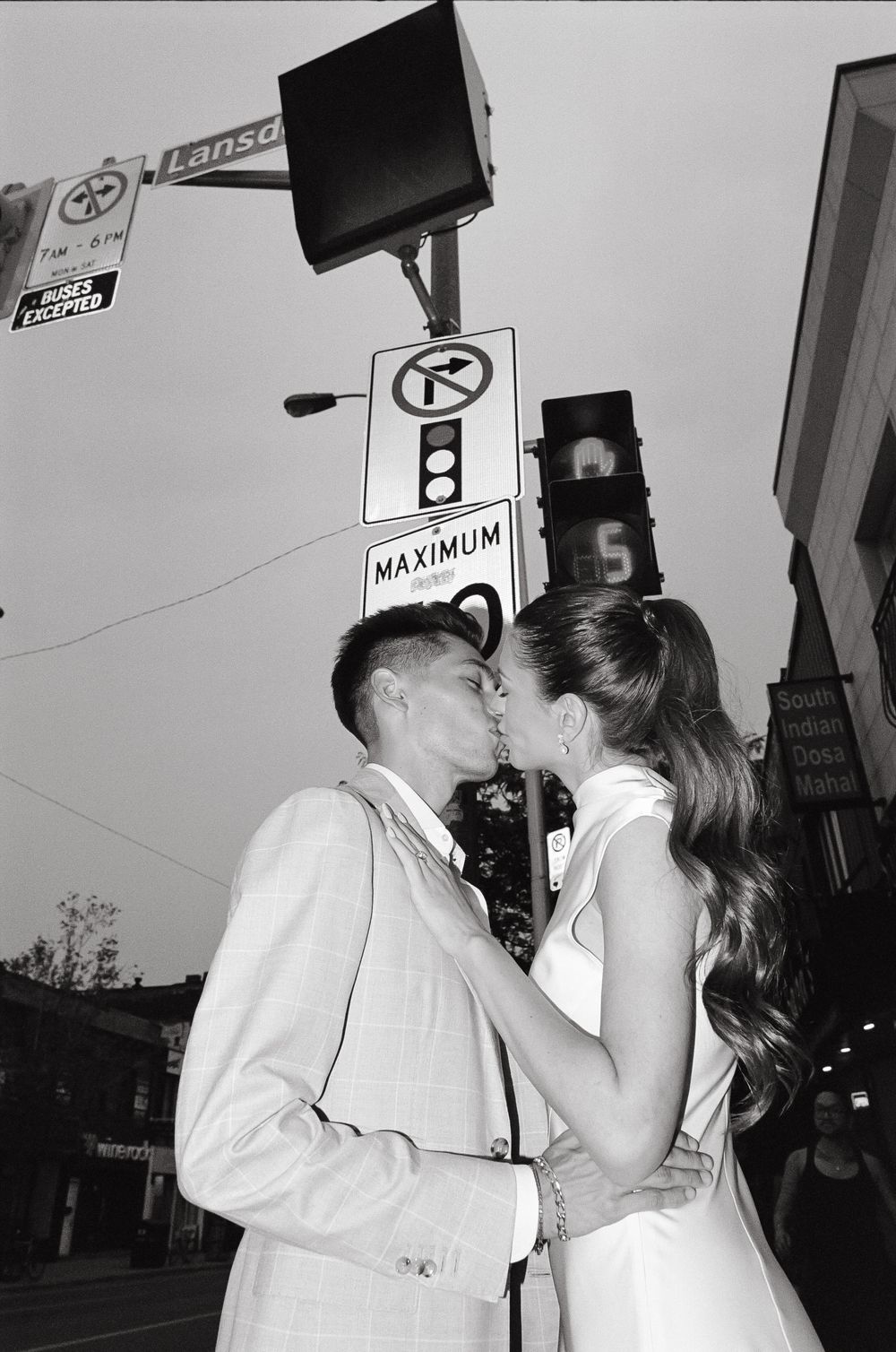 Couple sharing a romantic kiss at a city street intersection in black and white wedding photo.